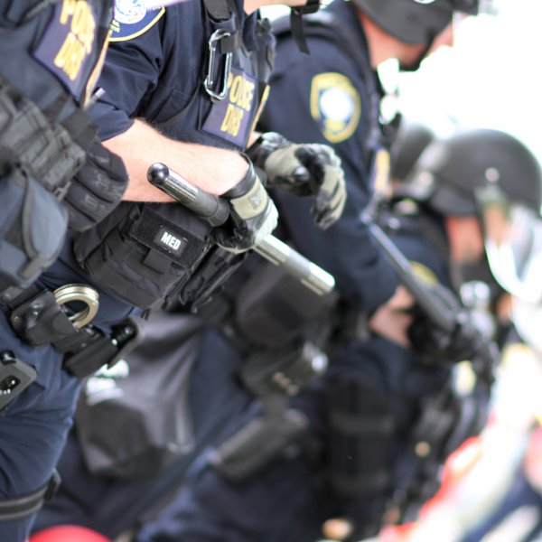 Law enforcement in riot suits during summer combating heat exhaustion and dehydration.